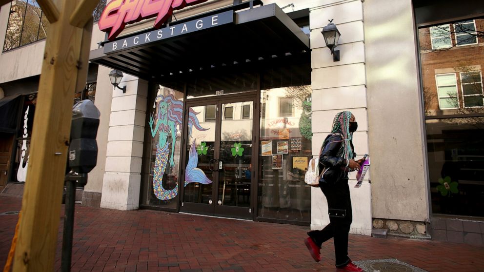 A person walks by Chicho’s Pizza Backstage, in Norfolk, Va., Saturday, March 19, 2022, where a fatal shooting took place outside the restaurant and bar earlier in the day. Newspaper reporter Sierra Jenkins was one of the people killed during the shoo