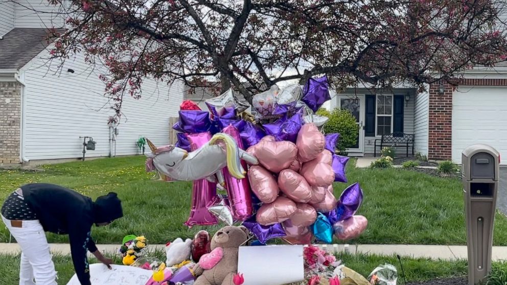 A man adjusts a sign near a memorial at the scene in the Columbus, Ohio neighborhood Friday, April 23, 2021 where 16-year-old Ma'Khia Bryant was fatally shot by police as she swung at two other people with a knife on Tuesday, April 20. (AP Photo/Farn