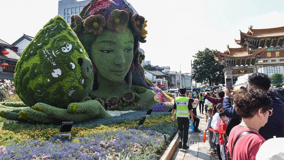 Tourists pass by a floral decoration celebrating the U.N. Biodiversity Conference (COP 15) in a park in Kunming, the host city, in southwestern China's Yunnan province, on Oct. 2, 2021. China has pledged $230 million to establish a fund to protect bi