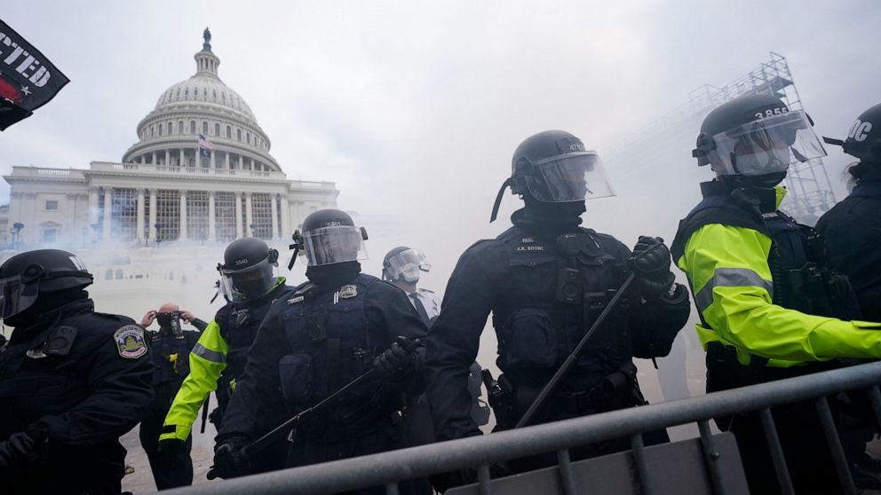 FILE - Police stand guard after holding off rioters who tried to break through a police barrier at the Capitol in Washington, on Jan. 6, 2021. Federal authorities say five Florida men affiliated with a militia group have been arrested on charges that