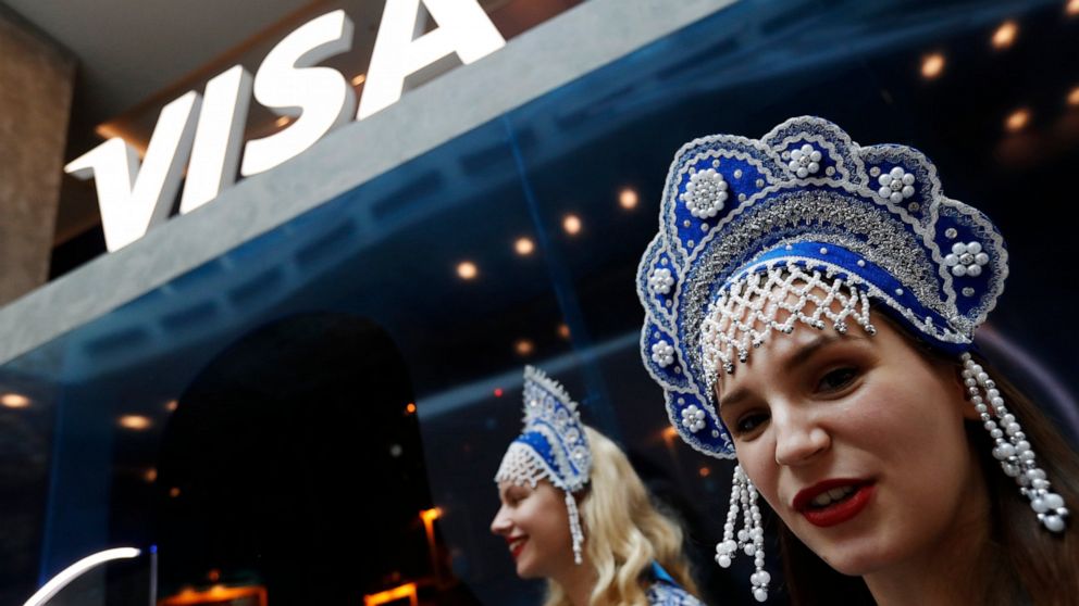 FILE - In this July 5, 2018 photo, women wearing traditional head dresses wait to greet Visa cardholders who won trips to the 2018 soccer World Cup, at the Marriott Novy Arbat Hotel, taken over by visa for the duration of the World Cup in Moscow, Rus