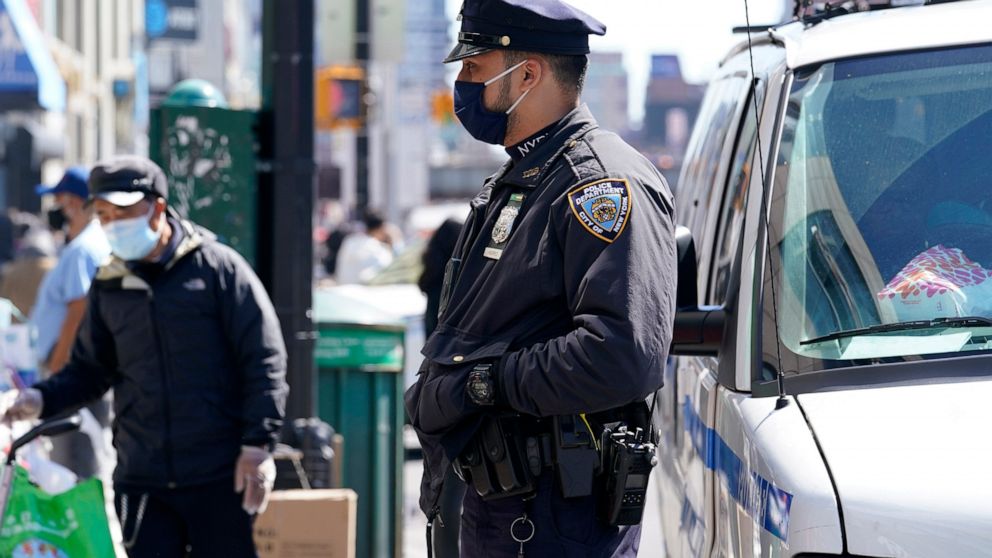 New York City Police Department Officer Rodney Hierro, right, keeps an eye on pedestrians and vendors along a busy section of Main Street in Flushing, a largely Asian American neighborhood, Tuesday, March 30, 2021, in the Queens borough of New York. 
