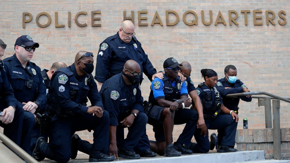 Members of the Austin Police Department kneel in front of demonstrators who gathered in Austin, Texas, Saturday, June 6, 2020, to protest the death of George Floyd, a black man who was in police custody in Minneapolis. Floyd died after being restrain