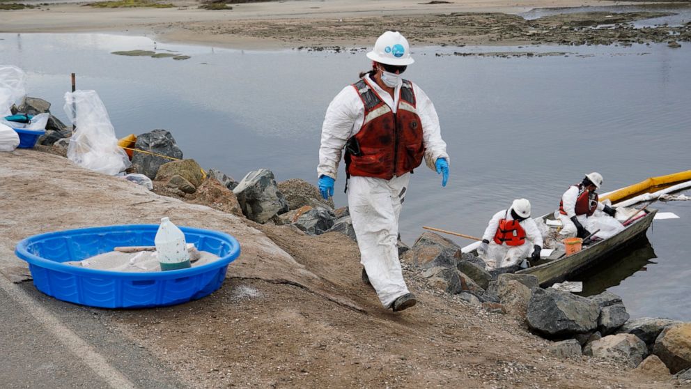 Cleanup crews, wearing protective suits, retrieve oil deposits around Talbert Marsh in Huntington Beach, Calif., Wednesday, Oct. 6, 2021. An oil spill sent up to 126,000 gallons of heavy crude into the ocean. It contaminated the sands of famed Huntin