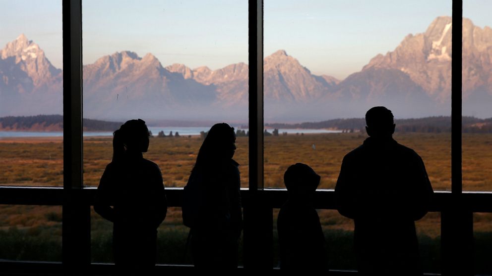 FILE - Visitors watch the morning sun illuminate the Grand Tetons from within the Great Room at the Jackson Lake Lodge in Grand Teton National Park in Wyoming on Aug. 28, 2016. Heather Mycoskie, 40, accused of intentionally providing wrong informatio
