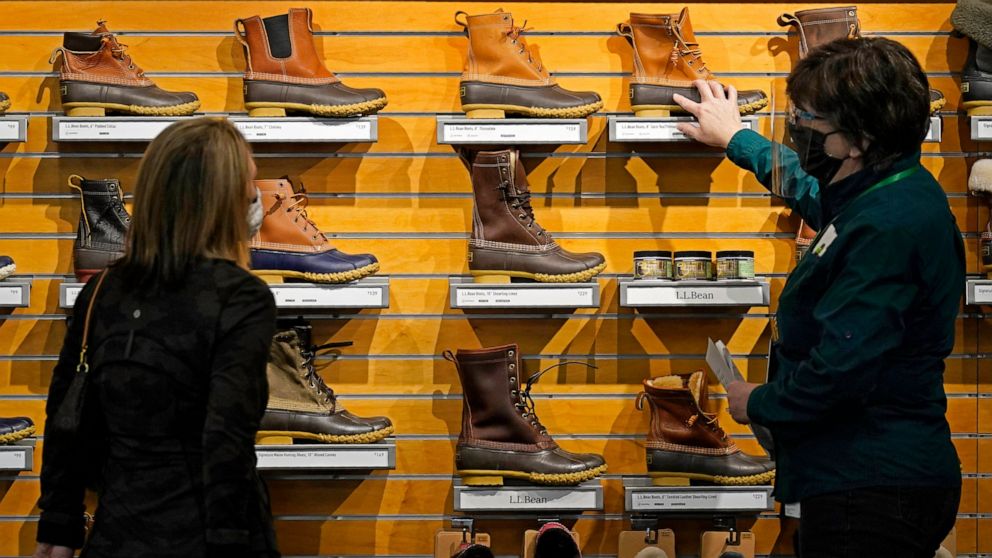 FILE - In this March 18, 2021 file photo, a salesperson helps a customer shopping for Bean Boots at the L.L. Bean flagship retail store in Freeport, Maine. U.S. consumer spending rebounded sharply in March while incomes soared, reflecting billions of