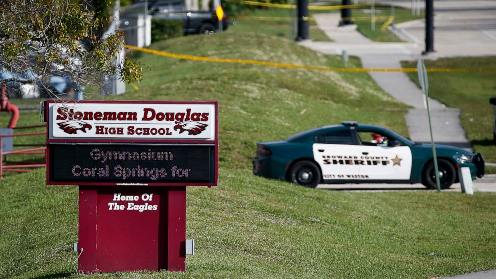 FILE- Law enforcement officers block off the entrance to Marjory Stoneman Douglas High School Feb. 15, 2018 in Parkland, Fla., following a deadly shooting at the school. The families of most of those killed in the 2018 Florida high school massacre ha