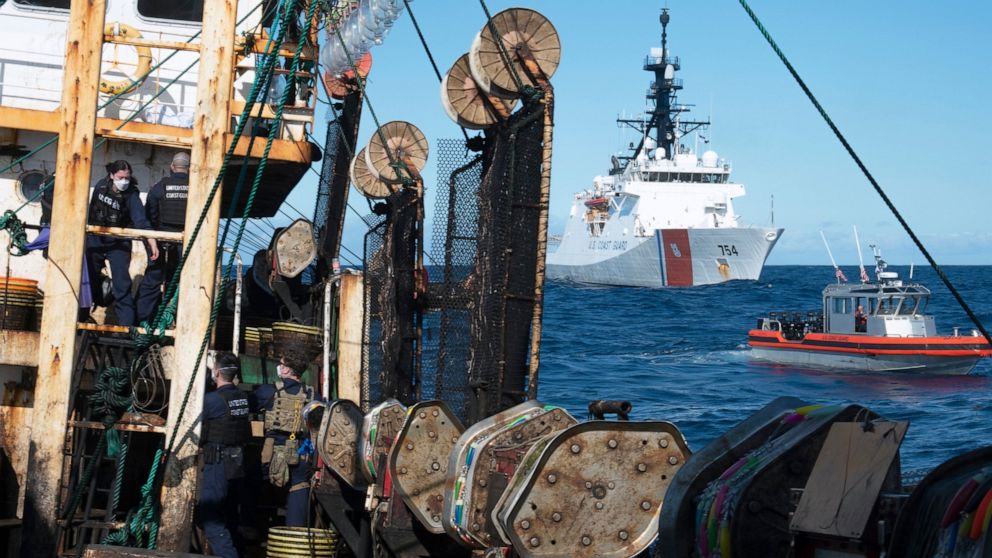 In this photo made available by the U.S. Coast Guard, guardsmen from the cutter James, seen at background right, conduct a boarding of a fishing vessel in the eastern Pacific Ocean, on Aug. 4, 2022. During the 10-day patrol for illegal, unreported or