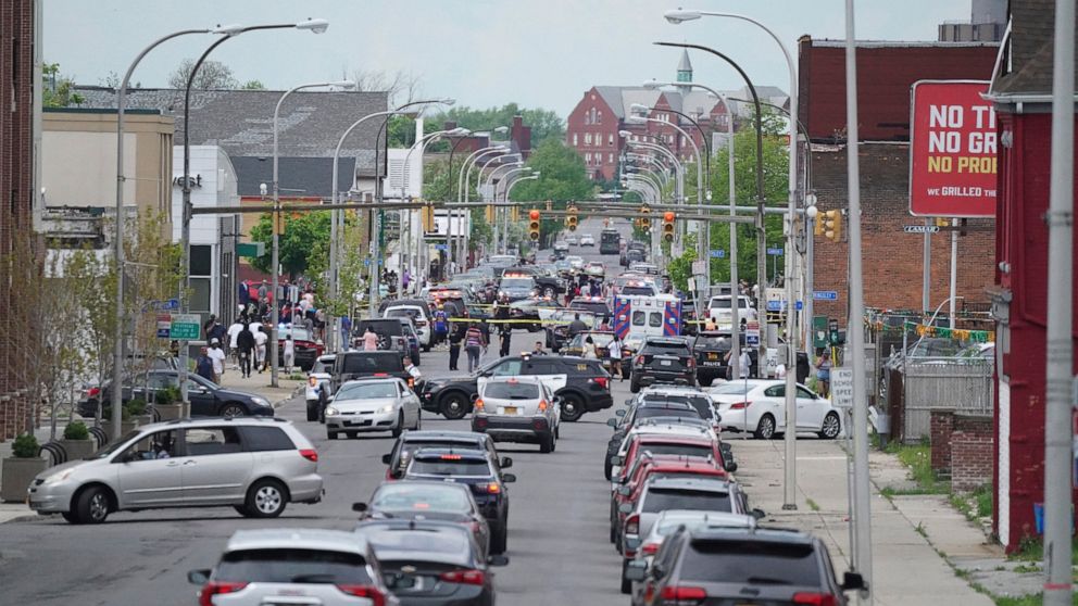 Police vehicles block off the street where at least 10 people were killed in a shooting at a supermarket, Saturday, May 14, 2022 in Buffalo, N.Y. Officials said the gunman entered the supermarket with a rifle and opened fire. Investigators believe th