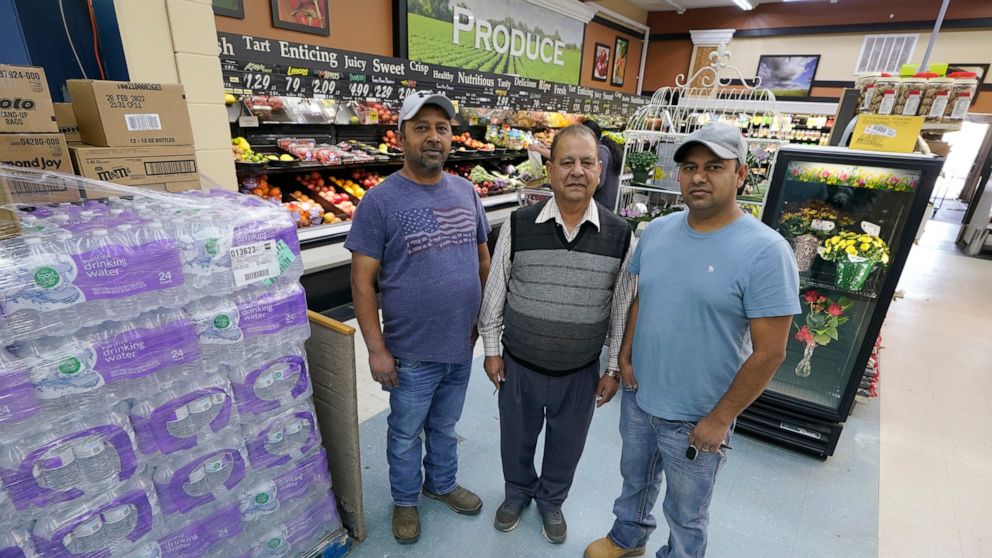 Singh Maan, center, poses for a photo with his sons CJ Maan, left, and Ricky Maan, right, Monday, Sept. 27, 2021, in the grocery store they own in Chester, Mont., near the scene where an Amtrak train derailed Saturday, killing three people and injuri