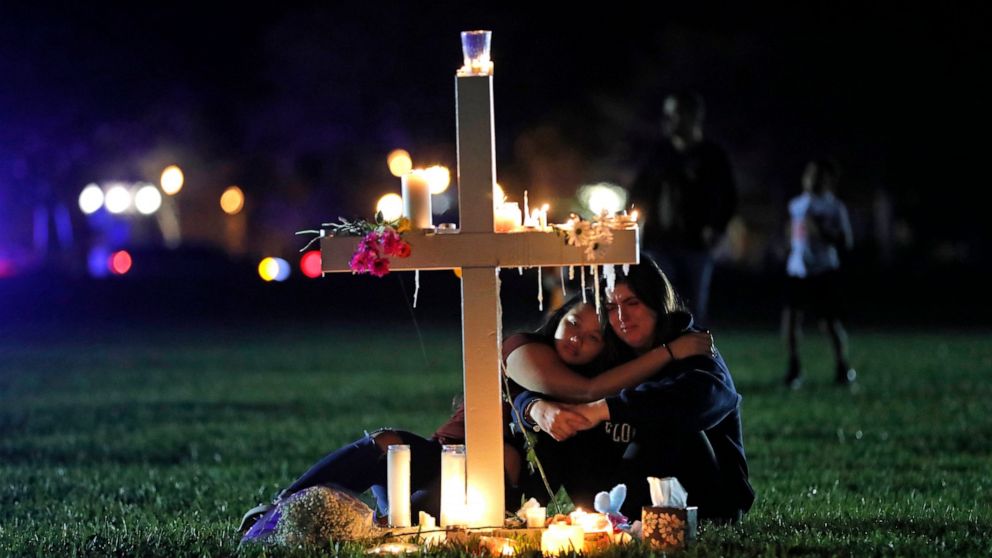 FILE - In this Feb. 15, 2018 file photo, people comfort each other as they sit and mourn at one of seventeen crosses, after a candlelight vigil for the victims of the shooting at Marjory Stoneman Douglas High School, in Parkland, Fla. Sorrow is rever