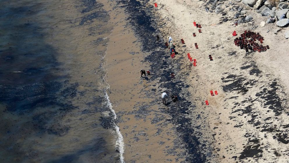 FILE - Volunteers fill buckets with oil near Refugio State Beach after an oil spill north of Goleta, Calif., May 20, 2015. A judge has approved a $230 million lawsuit settlement by the owners of a pipeline that spilled more than 140,000 gallons of cr