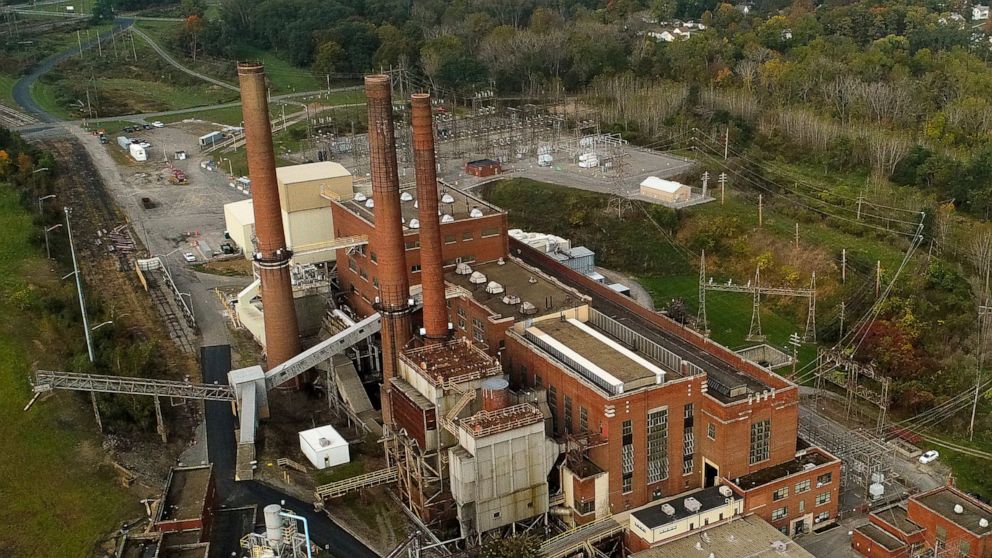 Smokestacks from the Greenridge Generation power plant tower above nearby homes, Friday, Oct. 15, 2021, in Dresden, N.Y. One Bitcoin mining operation in central New York came up with a novel solution in finding cheap energy to run the power-gobbling 