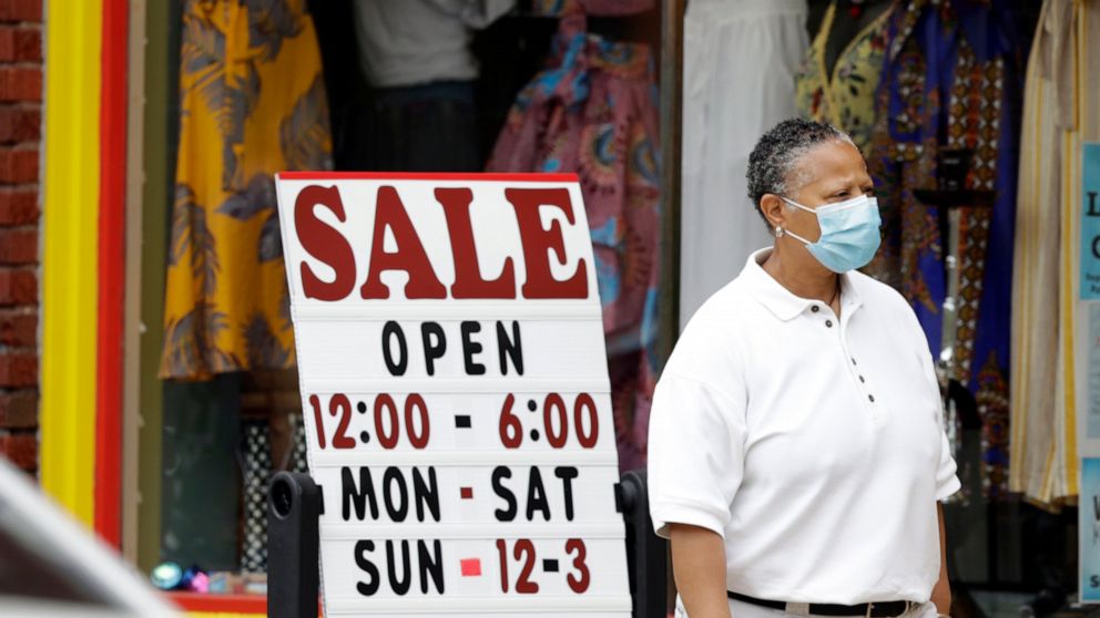 A woman walks past a boutique with a sale sign, Thursday, June 4, 2020, in Cleveland Heights, Ohio. The state says more than 34,000 Ohioans filed unemployment claims during the last week of May. That is the lowest figure since Ohio's stay-at-home ord