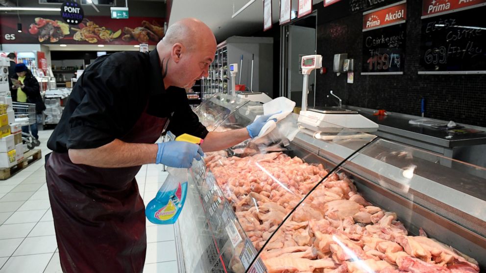 An employee disinfects the glass cover of a butcher counter to prevent the spread of the novel coronavirus in a food store in Budapest, Hungary, Wednesday, March 11, 2020. For most people, the new coronavirus causes only mild or moderate symptoms, su