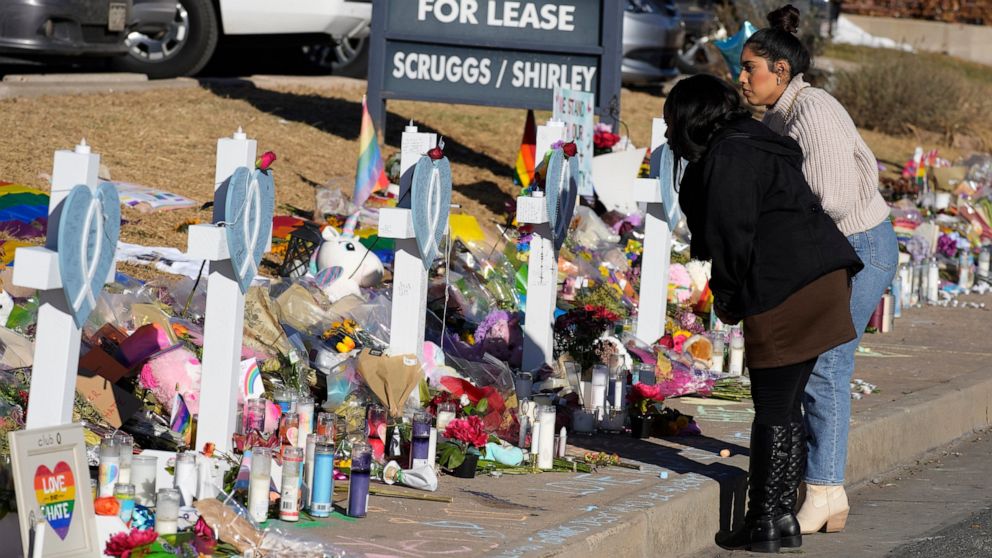 Mourners stand along the makeshift memorial to the victims of a weekend mass shooting at a nearby gay nightclub on Tuesday, Nov. 22, 2022, in Colorado Springs, Colo. Anderson Lee Aldrich opened fire at Club Q, in which five people were killed and oth
