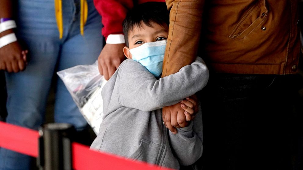 A migrant child holds onto a woman's arm as they wait to be processed by a humanitarian group after being released from U.S. Customs and Border Protection custody at a bus station, Wednesday, March 17, 2021, in Brownsville, Texas. Team Brownsville, a