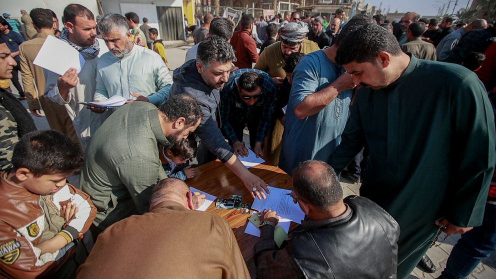 Supporters of the Shiite cleric Muqtada al-Sadr sign a pledge to stand against homosexuality or LGBTQ, outside a mosque in Kufa, Iraq, Friday, Dec. 2, 2022. Al-Sadr who announced his withdrawal from politics four months ago has broken a period of rel