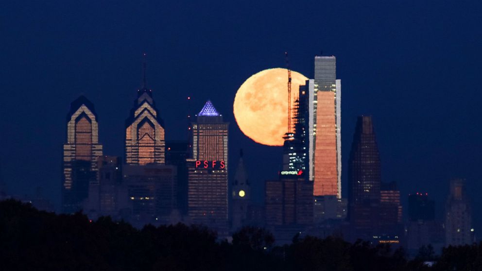 FILE - In this Nov. 14, 2016 file photo a supermoon sets behind the Philadelphia skyline. Bird Safe Philly announced on Thursday, March 11, 2021, that Philadelphia is joining the national Lights Out initiative, a voluntary program in which as many ex
