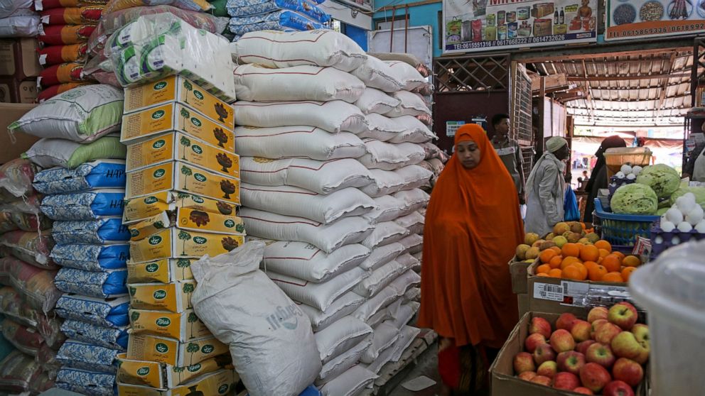 A woman walks past sacks of wheat flour piled high in the Hamar-Weyne market in the capital Mogadishu, Somalia Thursday, May 26, 2022. Families across Africa are paying about 45% more for wheat flour as Russia's war in Ukraine blocks exports from the