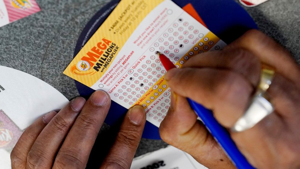 FILE - A customer fills out a Mega Millions lottery ticket at a convenience store in Northbrook, Ill., on Jan. 6, 2021. The holiday shopping season, for Mega Millions lottery ticket buyers, at least, is ramping up as officials say the estimated jackp