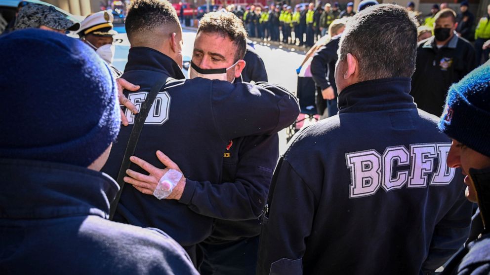 Baltimore firefighter John McMaster, center, who was injured in the fire and building collapse on Stricker Street Monday hugs fellow firefighters that were there to greet him as he was released from Shock Trauma Thursday, Jan. 27, 2022. (Jerry Jackso