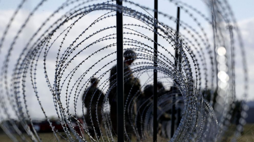 FILE--In this Nov. 3, 2018, file photo, members of the U.S. Army build a razor wire fence around area for tents near the U.S.-Mexico International bridge, in Donna, Texas. The U.S. government is working to open two new large tent facilities to tempor