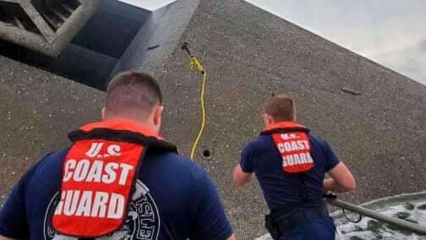 In this photo provided by the U.S. Coast Guard, Coast Guard Station Grand Isle 45-foot Response Boat-medium boat crew members attempt to throw a hammer at the hull of the SeaCor Power. The crew was attempting to make contact with potential survivors 
