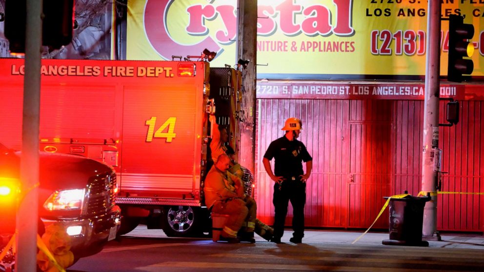 Firefighters stand near the scene of a fireworks explosion in Los Angeles on Wednesday, June 30, 2021. A cache of illegal fireworks seized at a South Los Angeles home exploded, damaging nearby homes and cars and causing injuries, authorities said. (A