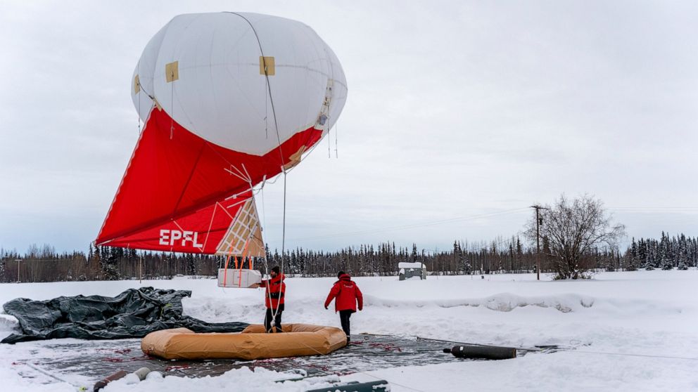 This Feb. 21, 2022, photo provided by the University of Alaska Fairbanks Geophysical Institute shows Swiss team members working with a tethered balloon and payload used to measure different characteristics of aerosols and trace gases in the atmospher