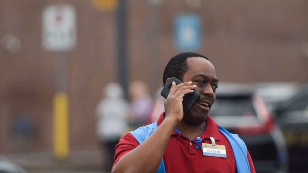 A Walmart employee speaks on a phone outside a Walmart store, Wednesday, Dec. 7, 2022, in Kennesaw, Ga. Police in suburban Atlanta say one person was shot and injured in a shooting near the automotive center at a Walmart store. Investigators said two