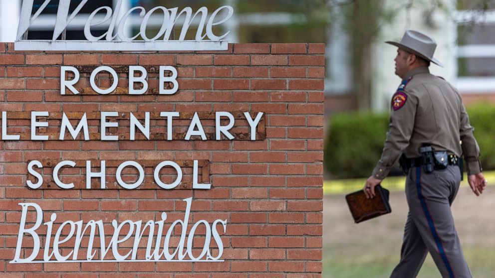 FILE - A state trooper walks past the Robb Elementary School sign in Uvalde, Texas, Tuesday, May 24, 2022, following a deadly shooting at the school. (William Luther/The San Antonio Express-News via AP, File)