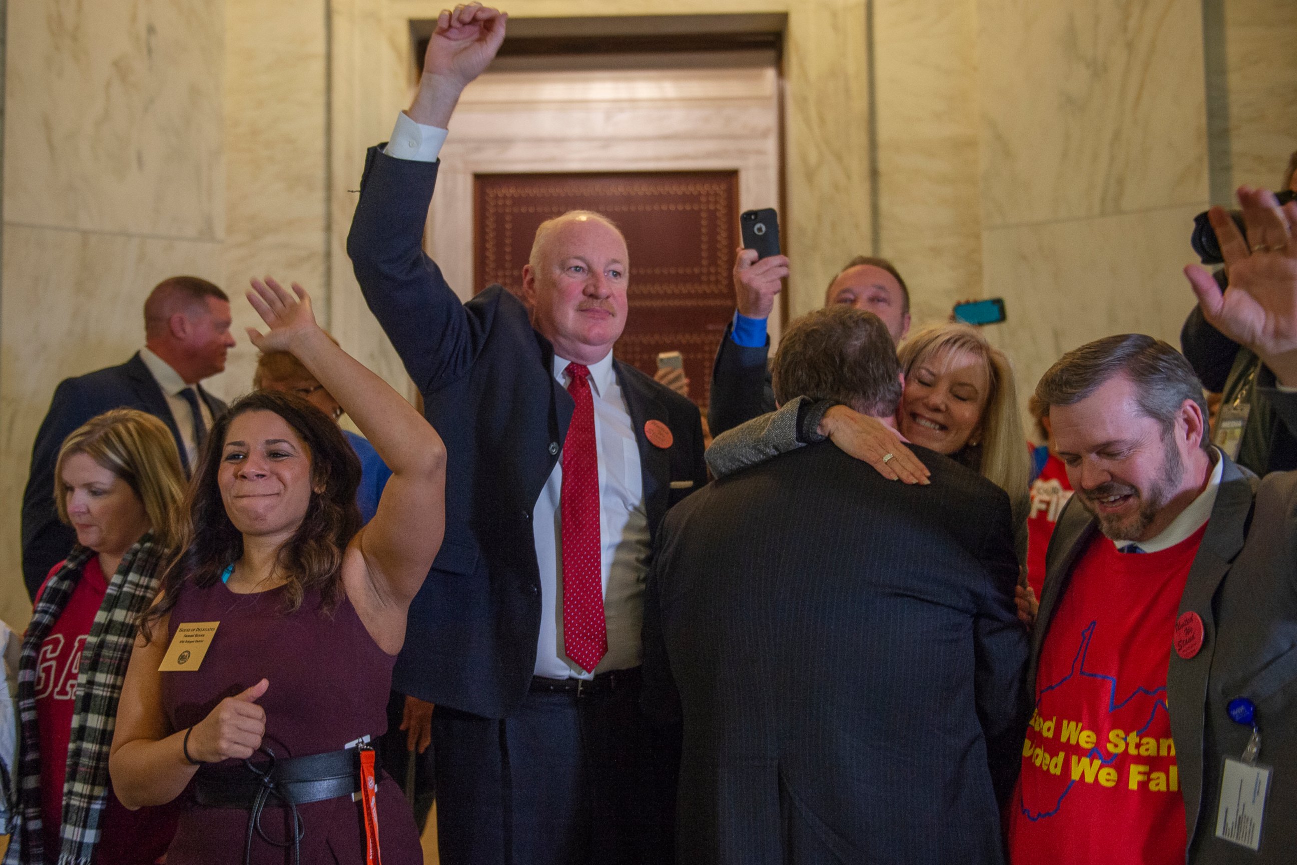 From left, Delegate Sammi Brown, D-Jefferson, West Virginia Education Association President Dale Lee and West Virginia School Service Personnel Association Executive Director Joe White raise their hands as teachers and school personnel celebrate afte