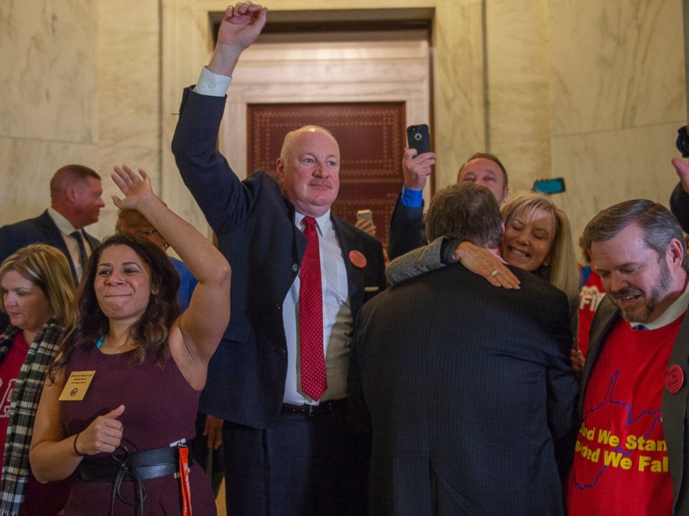 From left, Delegate Sammi Brown, D-Jefferson, West Virginia Education Association President Dale Lee and West Virginia School Service Personnel Association Executive Director Joe White raise their hands as teachers and school personnel celebrate afte