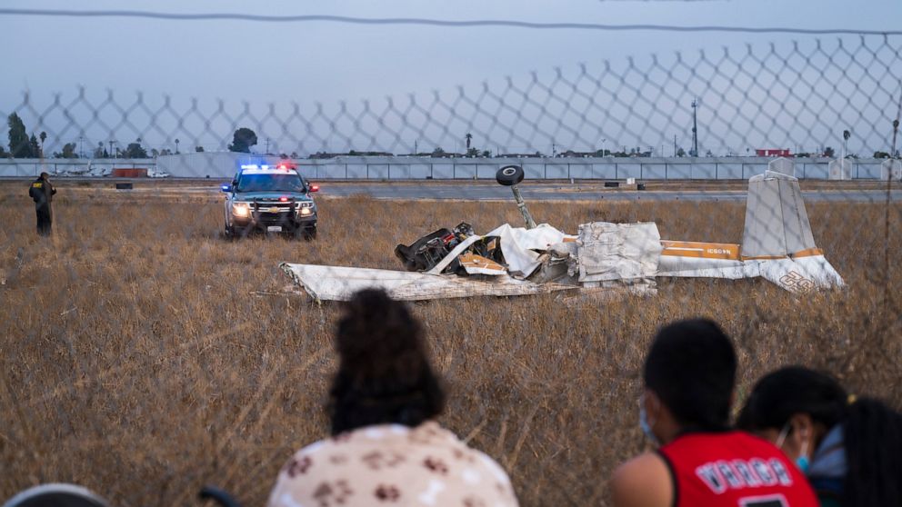 People look at the wreckage from a plane crash at Watsonville Municipal Airport in Watsonville, Calif., Thursday, Aug. 18, 2022. (AP Photo/Nic Coury)