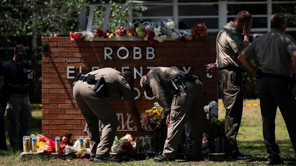 Two Texas Troopers light a candle at Robb Elementary School in Uvalde, Texas, Wednesday, May 25, 2022. Desperation turned to heart-wrenching sorrow for families of grade schoolers killed after an 18-year-old gunman barricaded himself in their Texas c