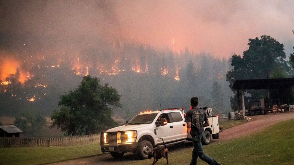 A man runs to a truck as a wildfire called the McKinney fire burns in Klamath National Forest, Calif., on Saturday, July 30, 2022. (AP Photo/Noah Berger)