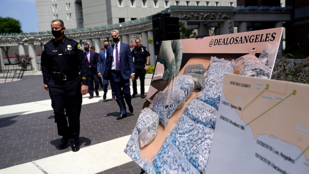 FILE - Officials walk past images of illegal drugs outside the Edward R. Roybal Federal Building on May 13, 2021, in Los Angeles. Authorities say a teenage girl died Tuesday night, Sept. 13, 2022, of an apparent overdose at a Los Angeles high school 