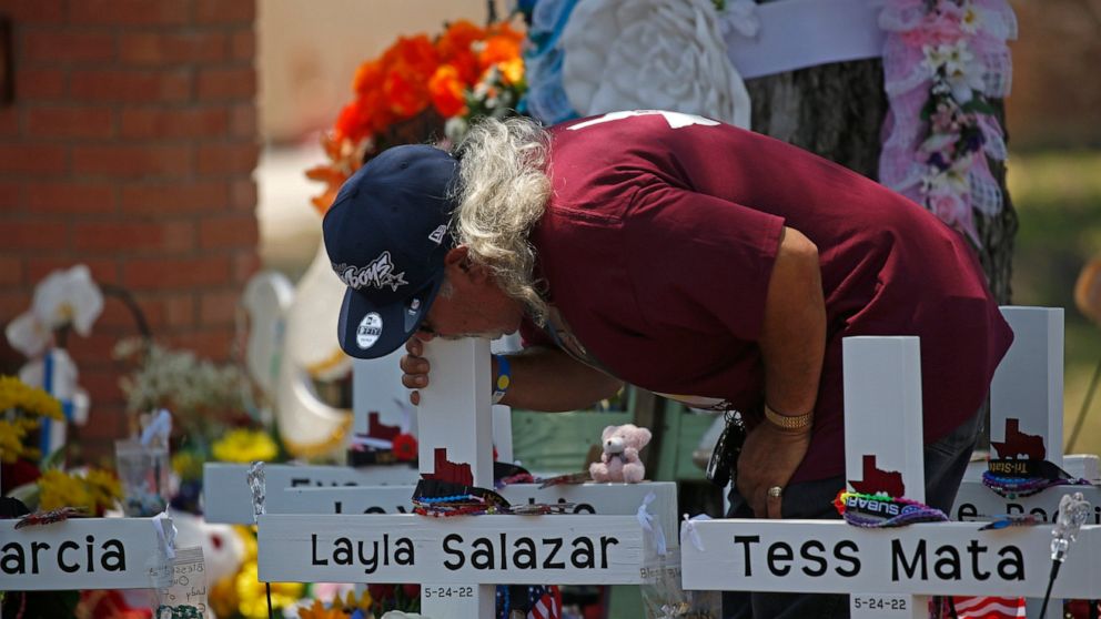 A man kisses the cross of Layla Salazar at a memorial outside Robb Elementary School to honor the victims killed in this week's school shooting in Uvalde, Texas, Saturday, May 28, 2022. (AP Photo/Dario Lopez-Mills)