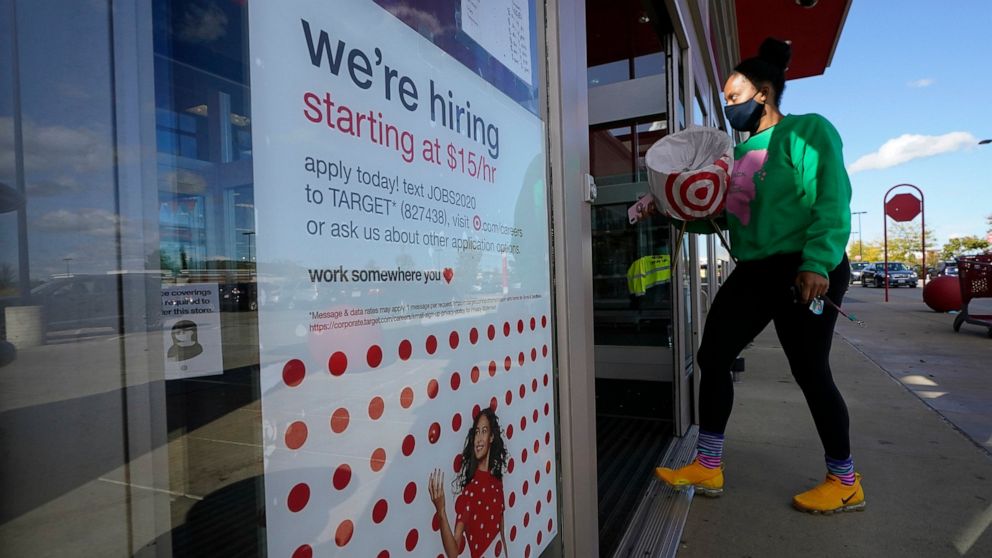 FILE - In this Sept. 30, 2020, file photo, a passerby walks past a hiring sign while entering a Target store in Westwood, Mass. The number of Americans applying for unemployment benefits edged higher last week to 745,000, a sign that many employers c