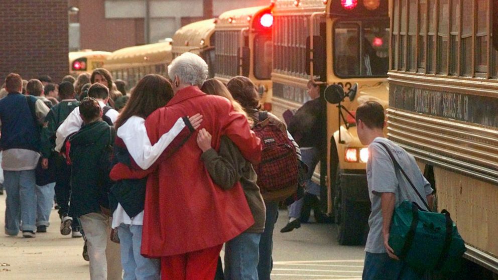 FILE - Students arriving at Heath High School in West Paducah, Ky., embrace an unidentified adult on Tuesday, Dec. 2, 1997, after student Michael Carneal opened fire at the school the day before, leaving three students dead and five wounded. In the q