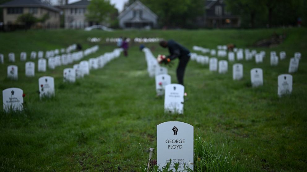 Community members lay flowers down near gravestone markers at the 'Say Their Names' cemetery Wednesday, May 25, 2022, in Minneapolis. The intersection where George Floyd died at the hands of Minneapolis police officers was renamed in his honor Wednes
