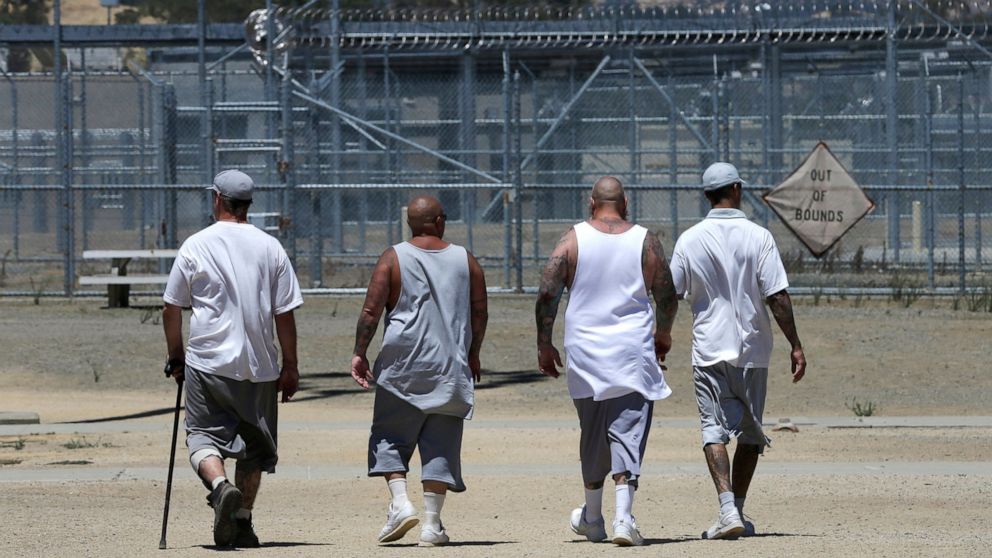 FILE - Inmates walk the exercise yard at the California Medical Facility in Vacaville, Calif., June 20, 2018. California would allow more ill and dying inmates to be released from state prisons under legislation that cleared the state Senate and head