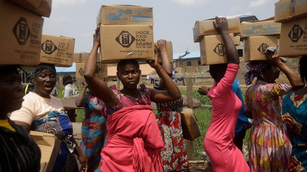 FILE - Residents of Oworonshoki Slum carry their food parcels distributed by the Lagos Food Bank Initiative, a non-profit nutrition focused initiative committed to fighting hunger and solving problems of Malnutrition for poor communities, in Lagos, N