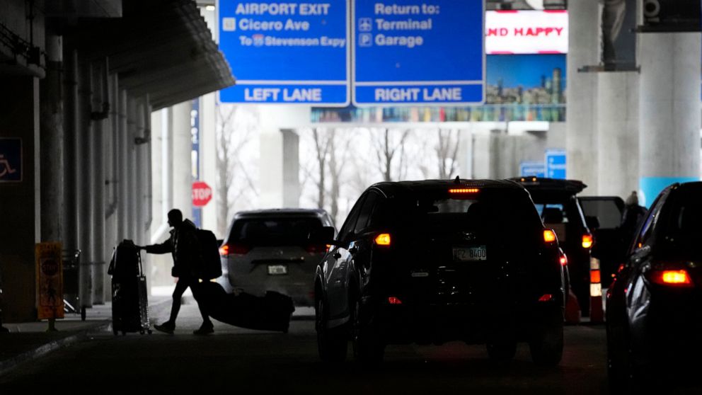 An airline passenger walks between ride share vehicles after arriving at Chicago's Midway Airport just days before a major winter storm Tuesday, Dec. 20, 2022, in Chicago. (AP Photo/Charles Rex Arbogast)
