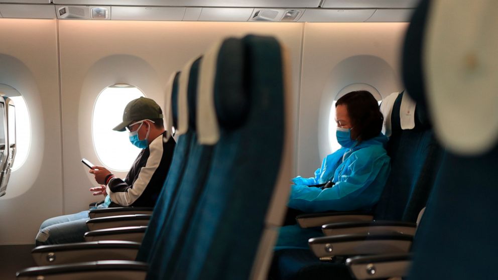 FILE - Passengers in protective suits and face masks sit on a plane in Hanoi, Vietnam, on Friday, Feb. 12, 2020. On Friday, July 8, 2022, the U.S. Transportation Department sent a notice to airlines that they should take steps during the seat-assignm