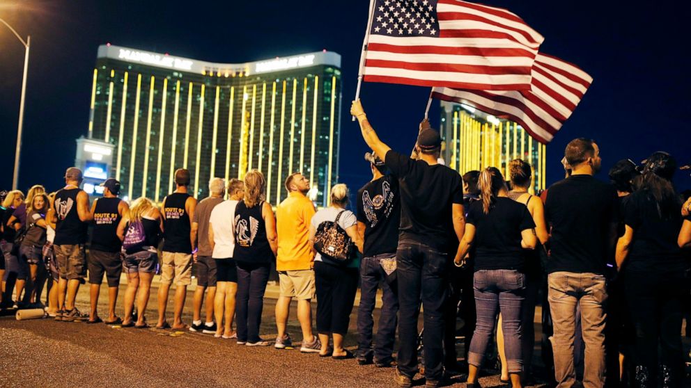 FILE - In this Oct. 1, 2018, file photo, people form a human chain around the shuttered site of a country music festival where a gunman opened fire on the first anniversary of the mass shooting in Las Vegas. People who died, will be remembered Friday