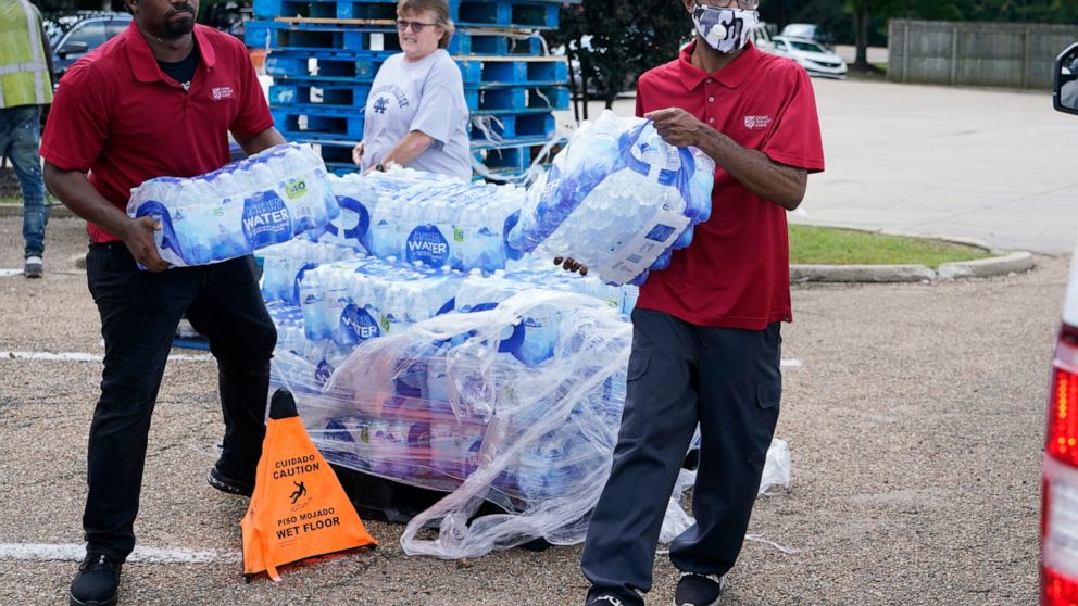 Salvation Army members carry cases of water to a waiting vehicle in Jackson, Miss., Wednesday, Aug. 31, 2022. The organization and a local Walmart store established a mid-morning distribution site to assist water needy residents. The recent flood wor