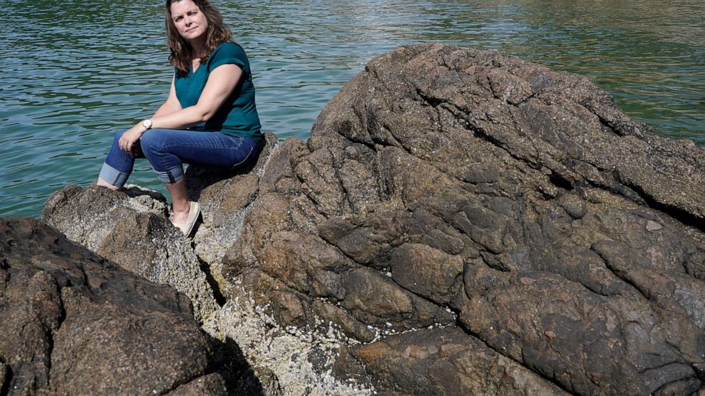 Endicott College history professor Elizabeth Matelski sits for a photo on Mingo Beach, in Beverly, Mass., Wednesday, June 15, 2022. The beach was named after enslaved African American Robin Mingo, who according to legend, was promised his freedom if 
