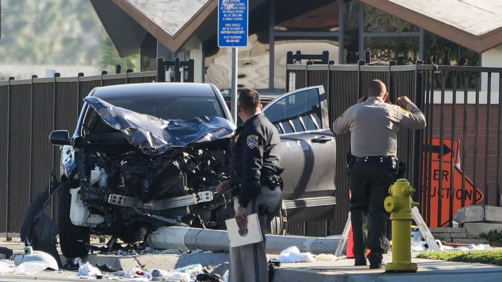 Two investigators stand next to a mangled SUV that struck Los Angeles County sheriff's recruits in Whittier, Calif., Wednesday, Nov. 16, 2022. The vehicle struck several Los Angeles County sheriff's recruits on a training run around dawn Wednesday, s